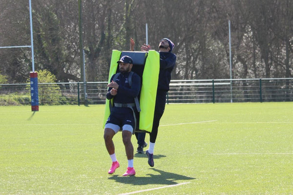 Two individuals on a rugby pitch with one using a Aerial contest bag.